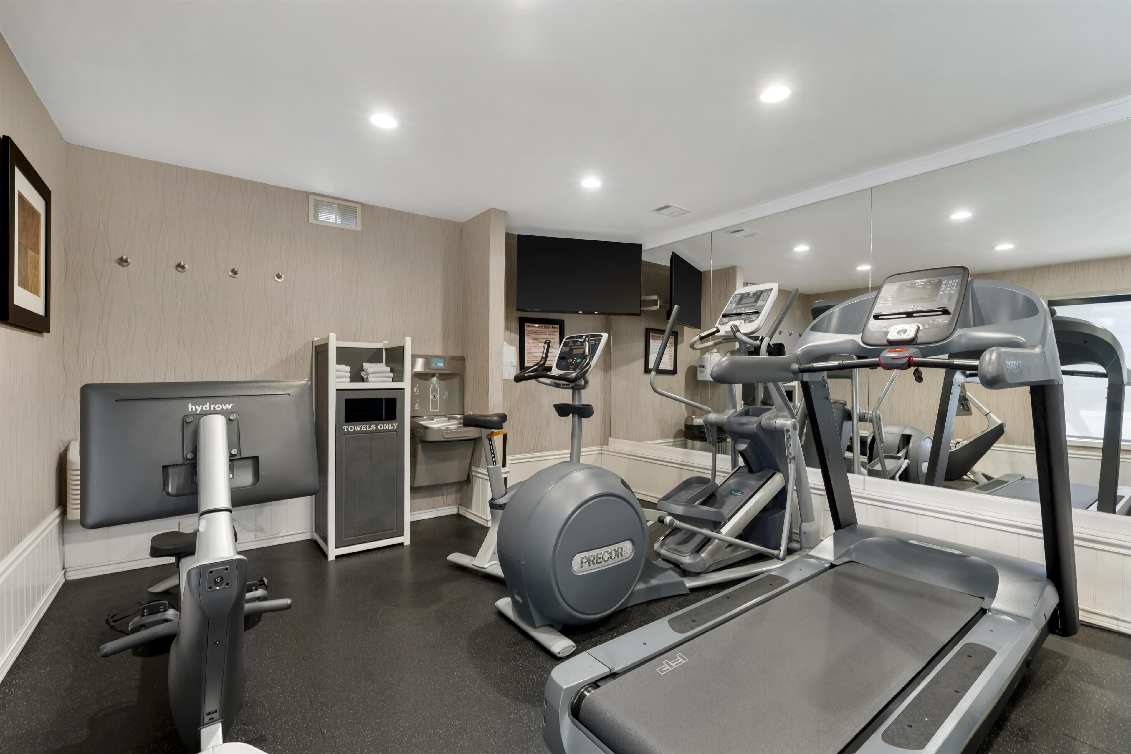 Une salle de sport moderne équipée de tapis de course, de vélos elliptiques et d’appareils de musculation.