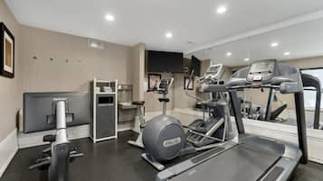 Un gimnasio moderno con cinta de correr, elíptica y máquinas de pesas.