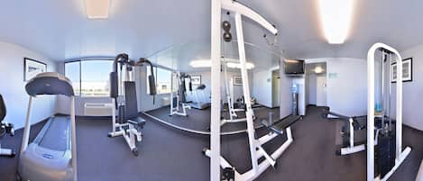 A gym with cardio equipment, weight machines, and a mirrored wall.