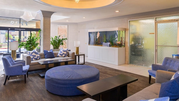 A modern lobby with a sofa set, chairs, a coffee table, and a large aquarium. - Quality Inn & Suites Montebello - Los Angeles (Montebello)