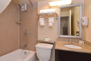 A bathroom with a bathtub, toilet, sink, and a towel rack with towels. - Quality Inn & Suites Montebello - Los Angeles (Montebello)