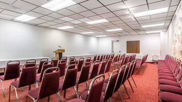 A conference room with rows of chairs, a podium, and a carpeted floor.