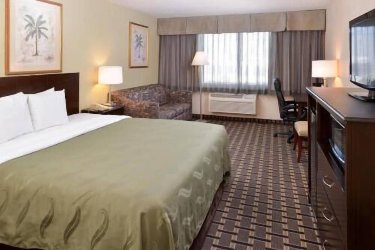 Ein Hotelzimmer mit einem großen Bett, einer Couch, einem Schreibtisch und einem Fernseher.