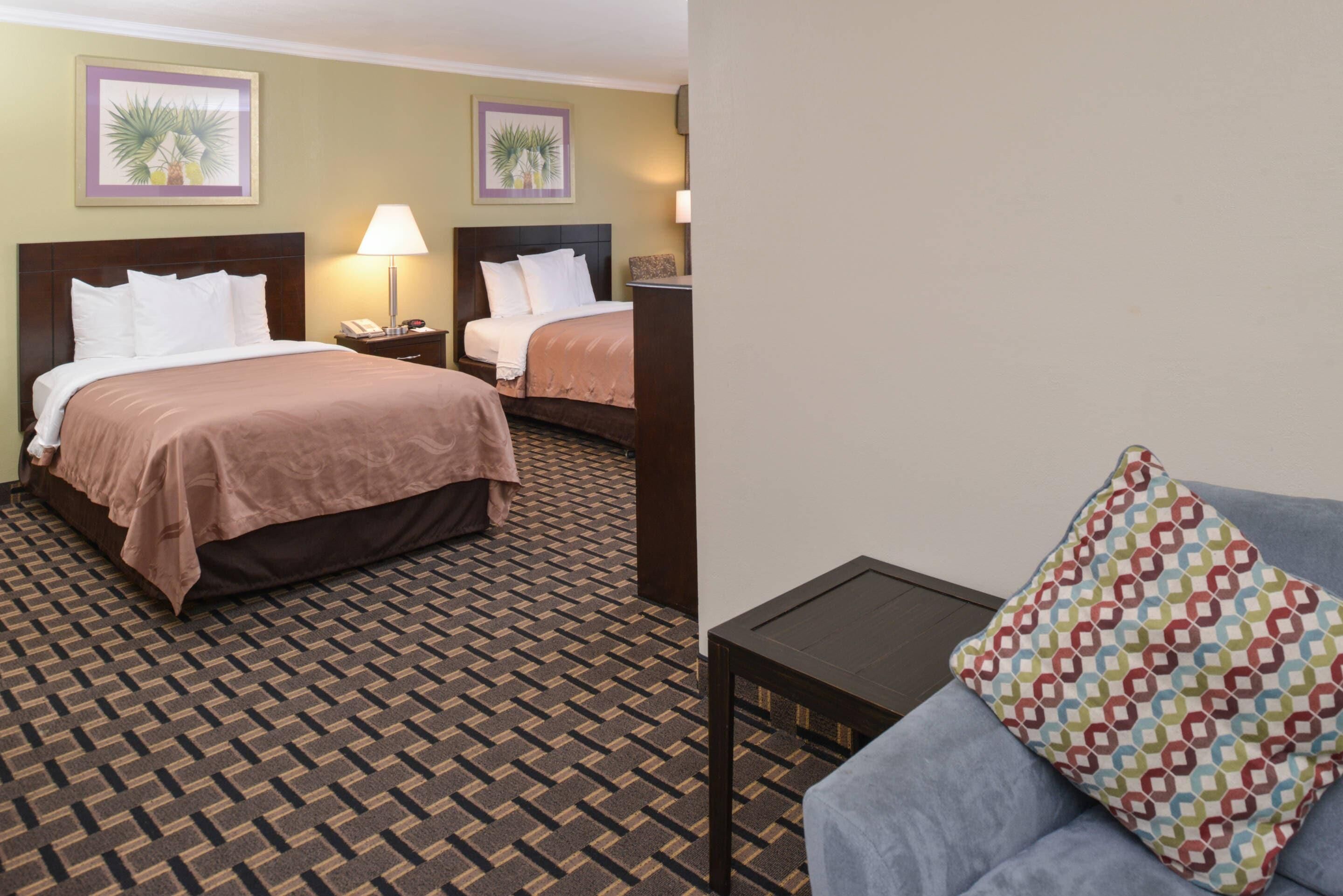 Una habitación de hotel con dos camas, una mesita y un sofá.