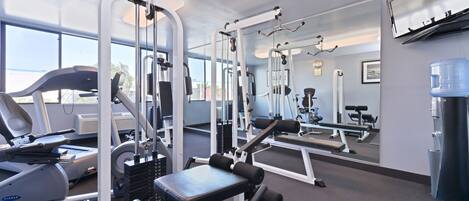 A gym with cardio machines, weightlifting equipment, and a water dispenser.