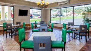 A restaurant with green and gray chairs, a large window, and a flat-screen TV on the wall. - Days Inn by Wyndham Dalton (Dalton)