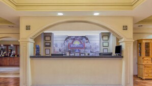 A reception area with a Days Inn sign, a stone wall backdrop, a reception desk, and a wooden cabinet to the right. - Days Inn by Wyndham Dalton (Dalton)