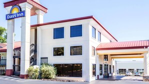 A Days Inn hotel with a red roof, white walls, and a sign with a sun logo. - Days Inn by Wyndham Dalton (Dalton)