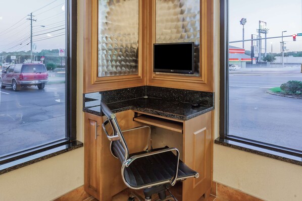 Un bureau d’angle équipé d’un bureau, d’une chaise et d’un téléviseur fixé au mur.