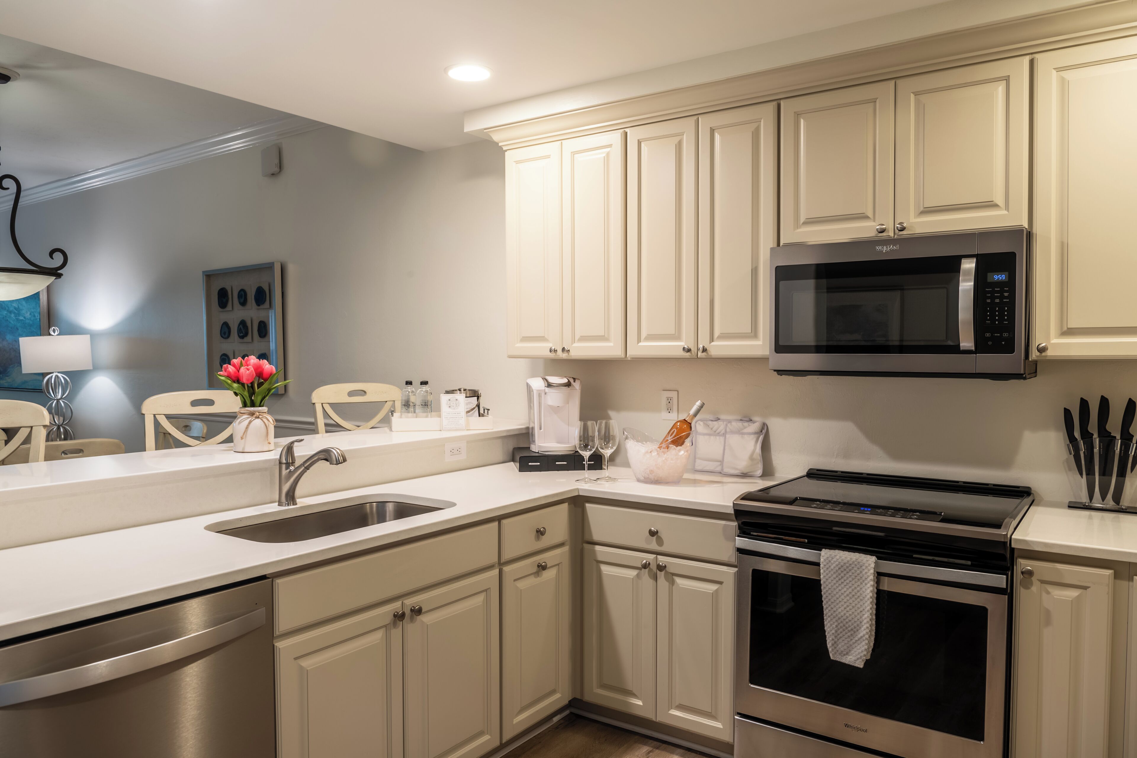 A modern kitchen with white cabinets, stainless steel appliances, and a built-in microwave.