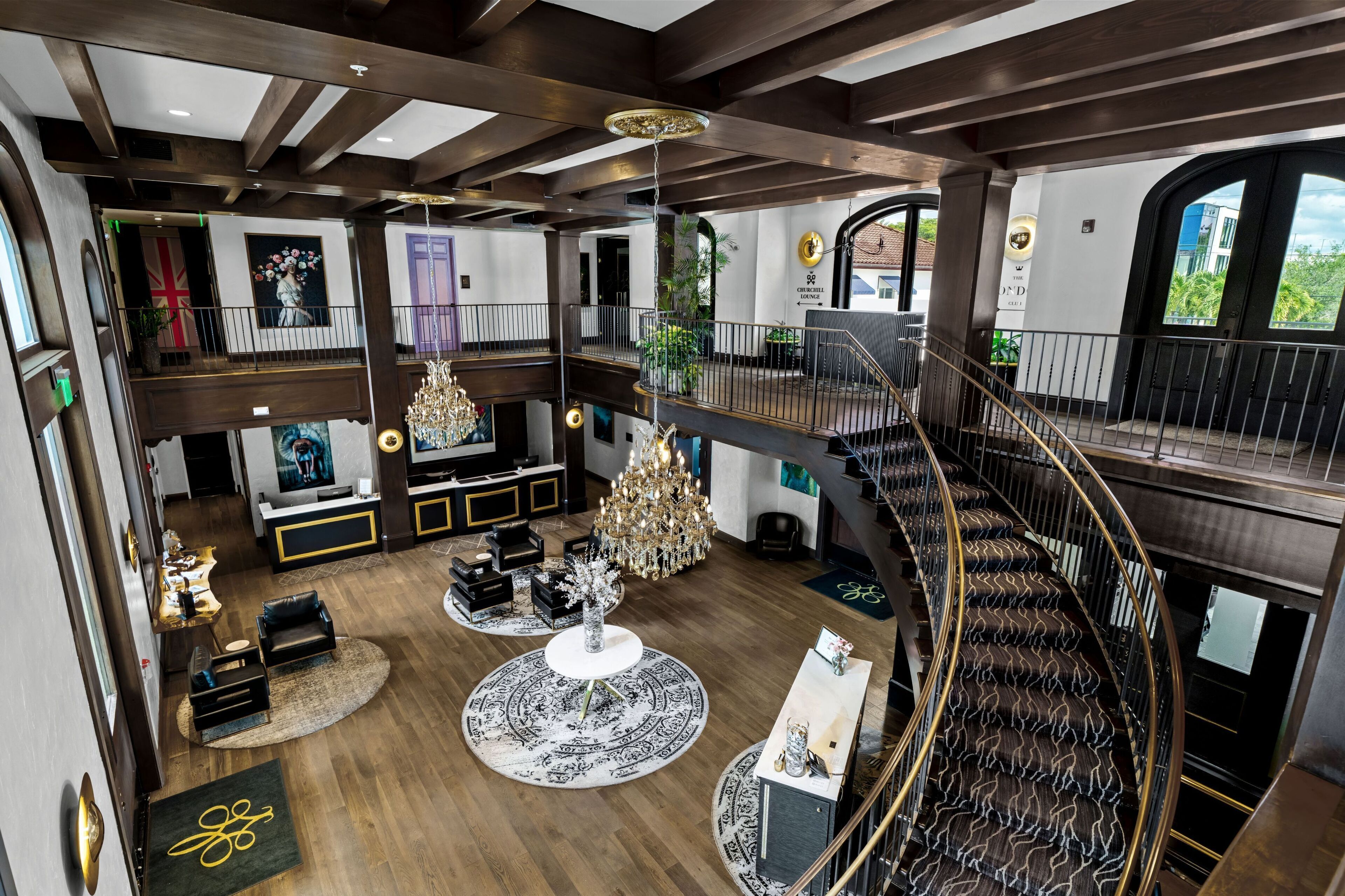 A spacious, multi-level hotel lobby with a grand chandelier, a staircase, and a view of the outdoors.