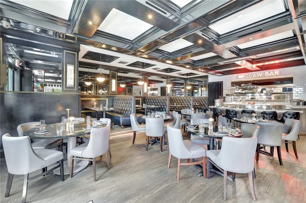 A modern restaurant with a bar area, seating arrangements, and a visible kitchen.