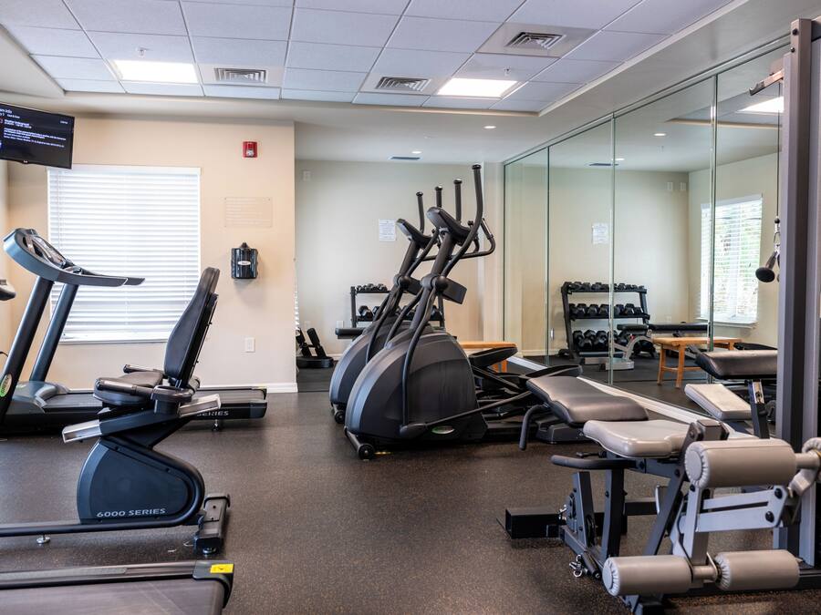 Une salle de sport équipée de tapis de course, de vélos elliptiques et d'appareils de musculation.