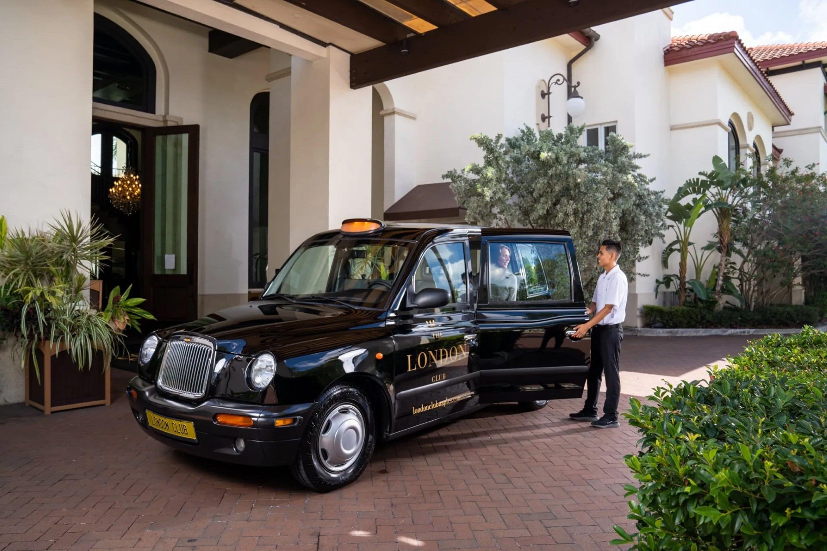 Eine schwarze Limousine vor einem Gebäude, an dem ein Schild mit der Aufschrift "LONDON CLUB" zu sehen ist.