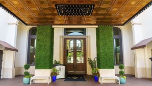 A hotel entrance with a wooden ceiling, a green wall, and a double door.