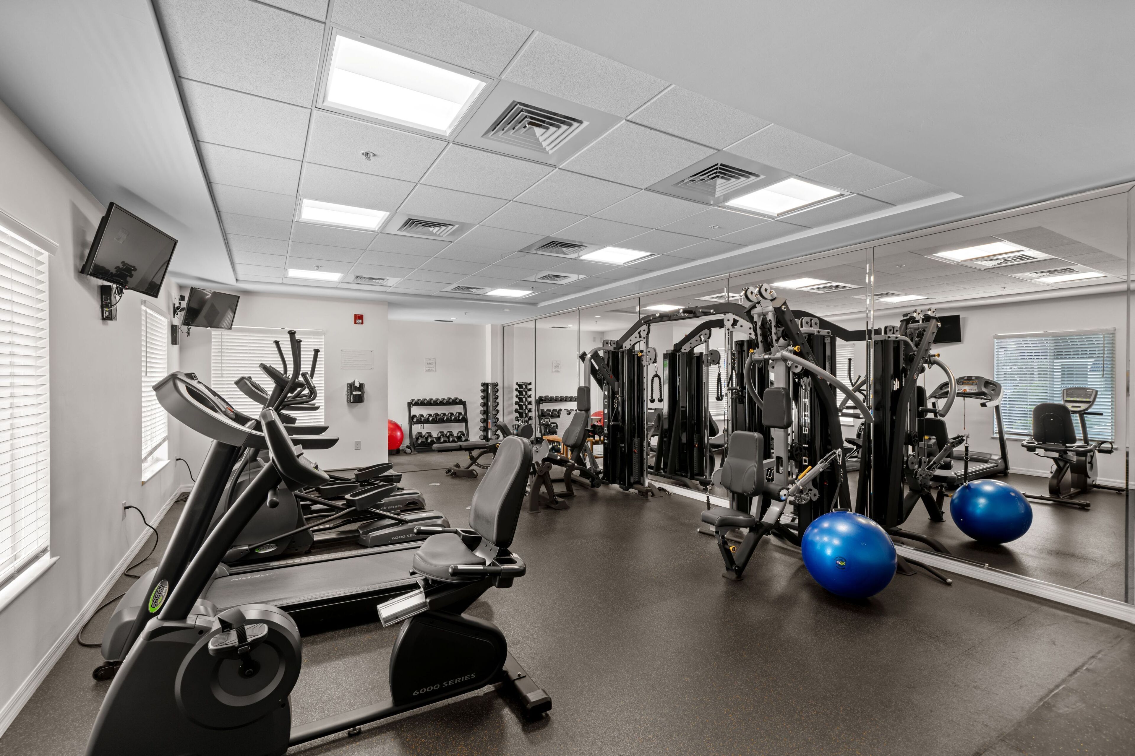 Academia com esteiras, aparelhos de musculação e bolas de exercício.