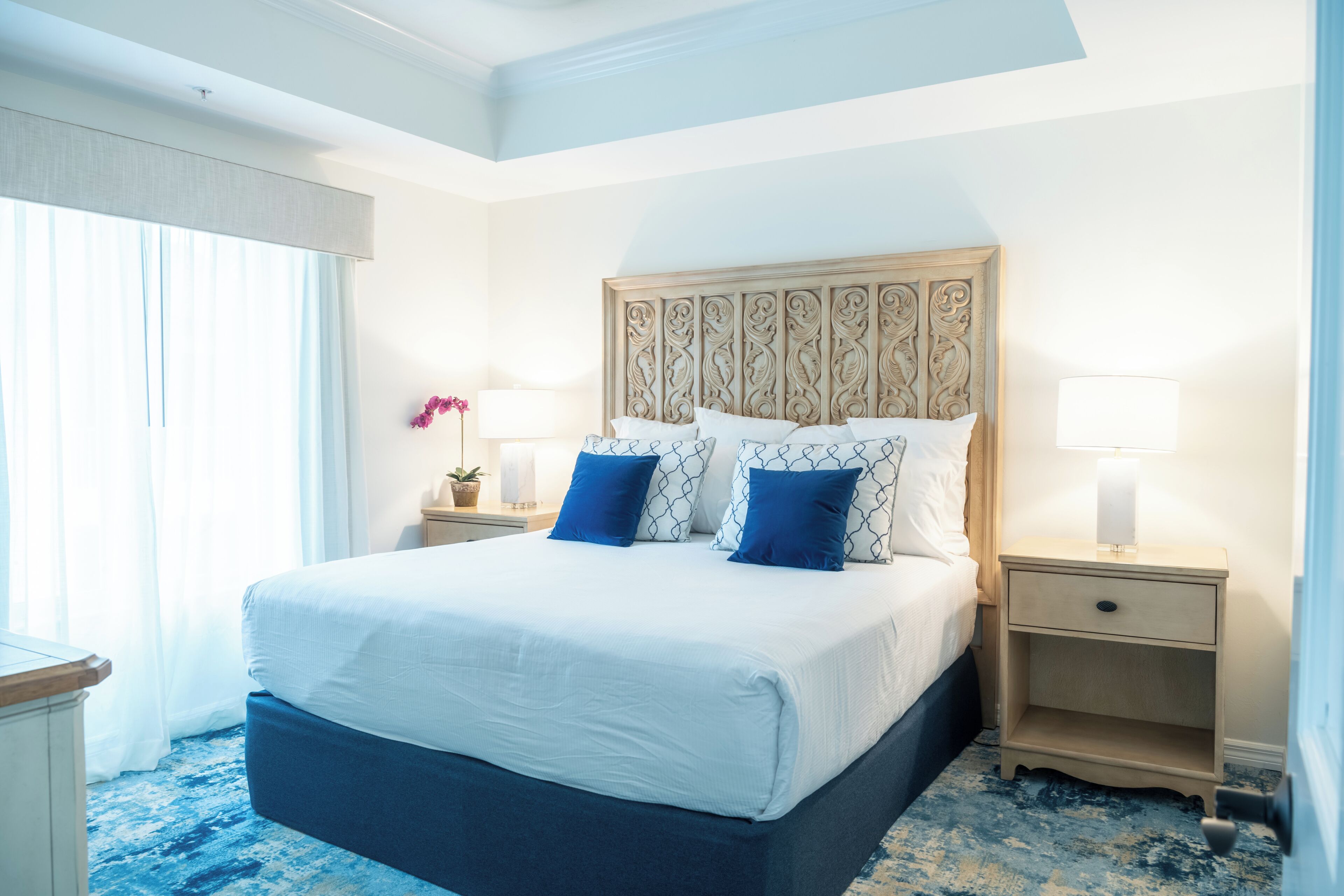 Une chambre d’hôtel avec un grand lit, deux tables de chevet et une fenêtre avec des rideaux.