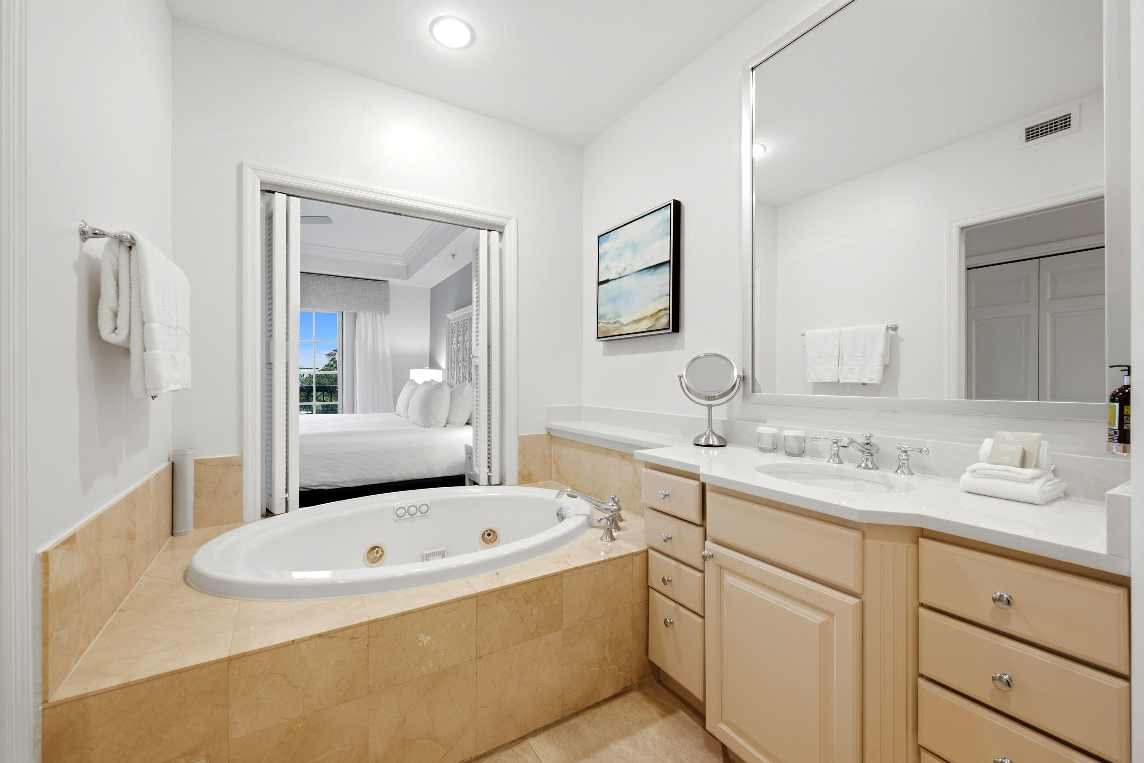 A modern bathroom with a bathtub, vanity, and a large mirror.