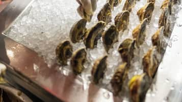 A person handling oysters on ice at a seafood market.
