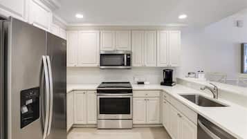 A modern kitchen with white cabinetry, stainless steel appliances, and a built-in oven.