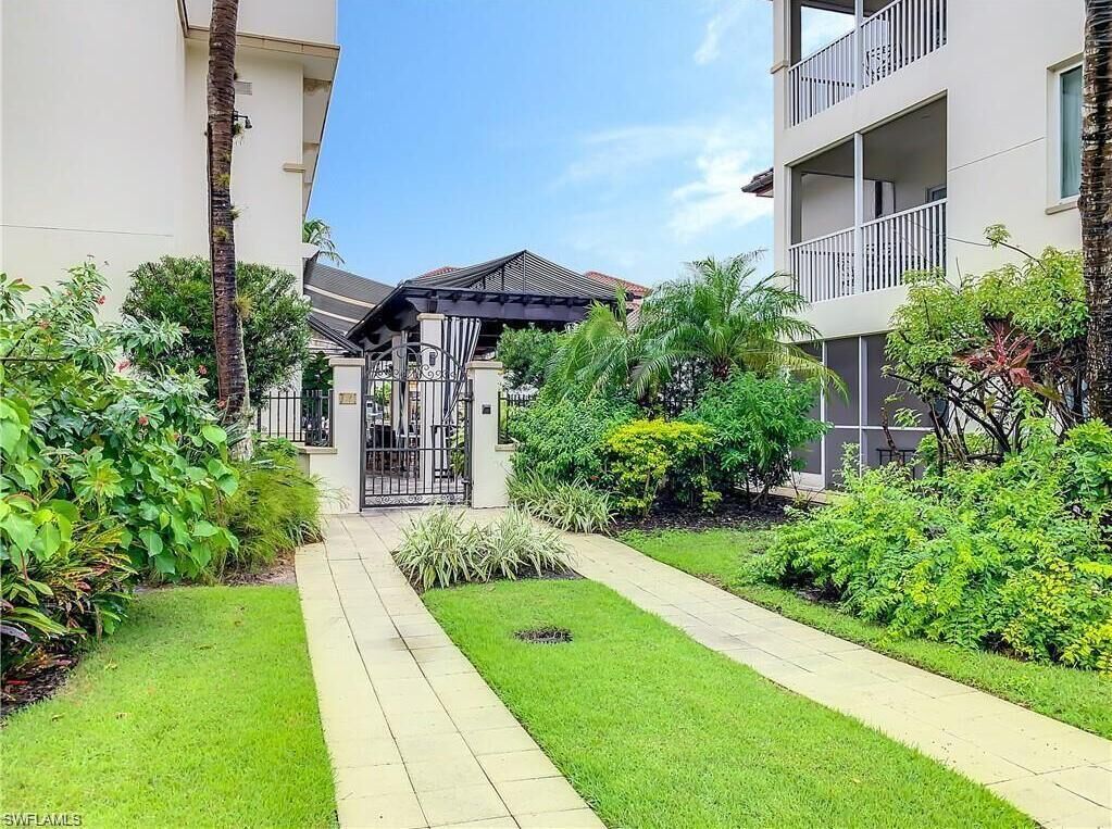 A gated entrance to a residential building with a pathway leading to a covered area.