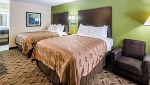 A hotel room with two beds, a chair, and a green wall. - Quality Inn Tanglewood (Roanoke)