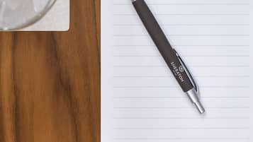 Une table en bois avec un verre d’eau, une tranche de citron vert, un carnet et un stylo.