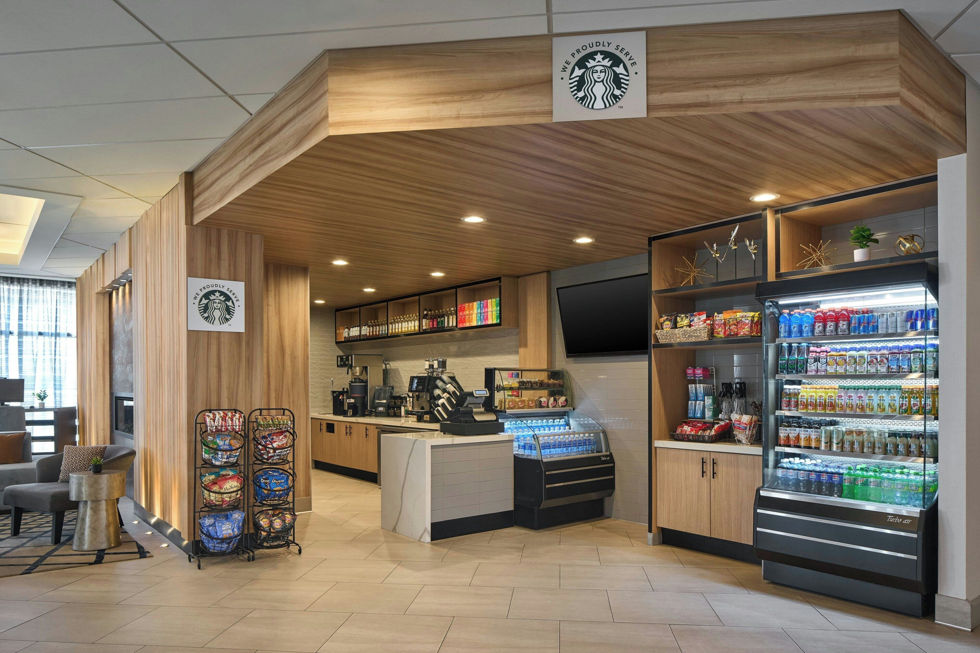 A Starbucks coffee shop with a wooden interior, a seating area, and a refrigerated display case.