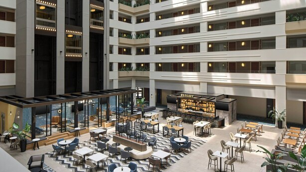 A multi-level hotel lobby with a central atrium, seating areas, and a bar/lounge. - Sheraton Suites Chicago O'Hare (Rosemont)