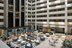 A multi-level hotel lobby with a central atrium, seating areas, and a bar/lounge. - Sheraton Suites Chicago O'Hare (Rosemont)