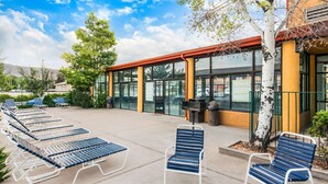 A building with a glass facade, outdoor seating area with metal chairs, and a tree. - Quality Inn Cedar City - University Area (Cedar City)