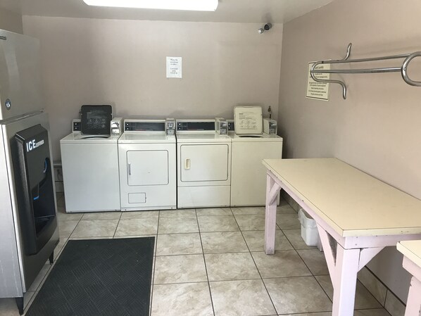 Un área de lavandería con refrigerador, lavadora, secadora y una mesa.