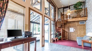 A spacious living area with a wooden desk, a computer, and a sofa. A staircase leads to an upper level with a balcony. - Quality Inn Cedar City - University Area (Cedar City)