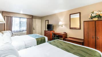A hotel room with two beds, a desk, a television, a mirror, and a window with curtains.