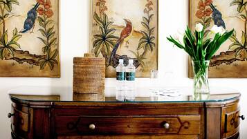 Un mueble de madera con tapa de cristal, decorado con una cesta trenzada, dos botellas de agua y un jarrón con flores.