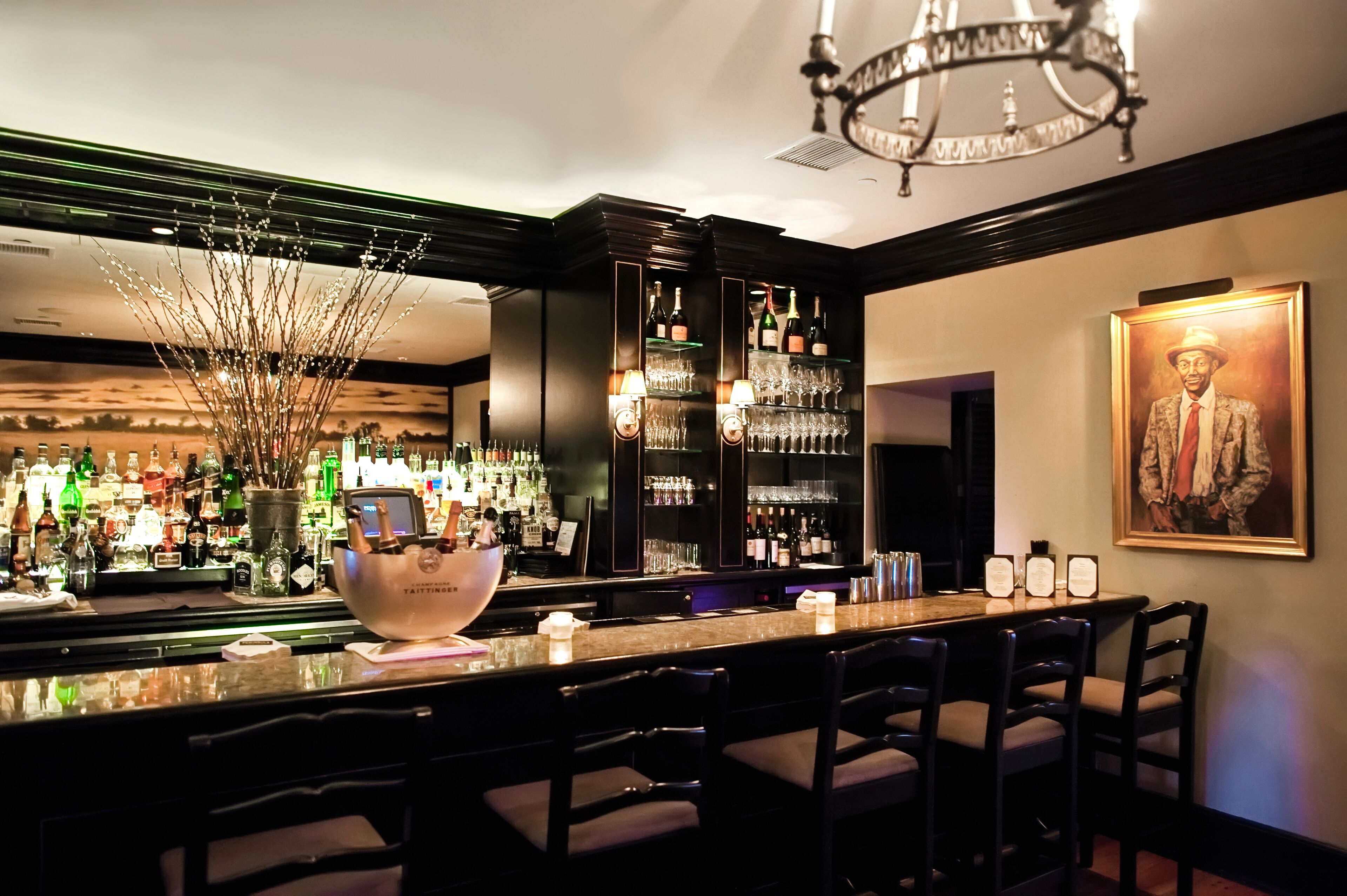 Een bar met een lange toonbank, verschillende zithoeken en een ruime keuze aan flessen en glazen.