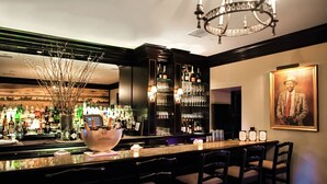 A bar area with a long counter, multiple seating options, and a variety of bottles and glasses.