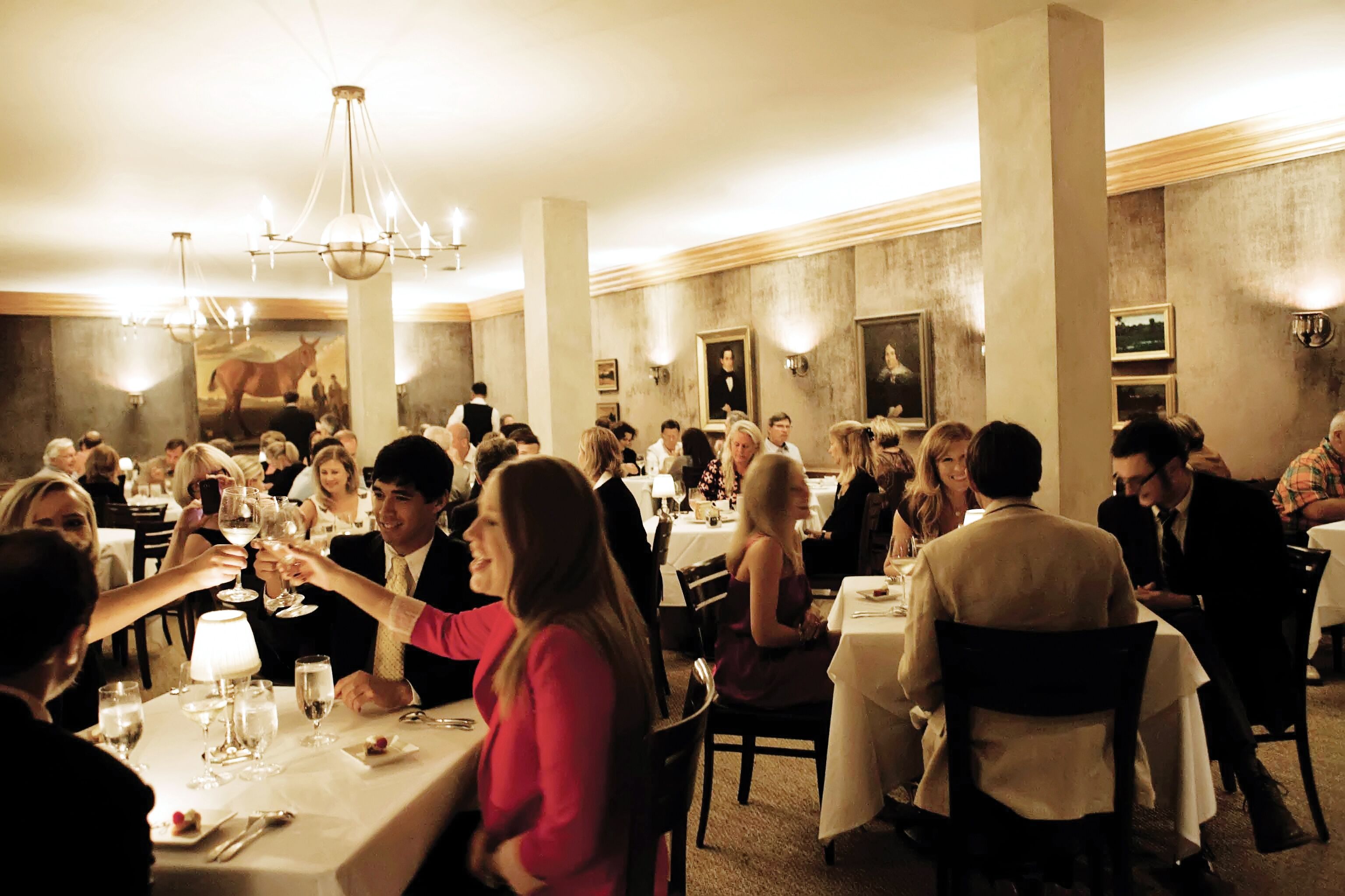 A formal dining room with multiple tables and guests.