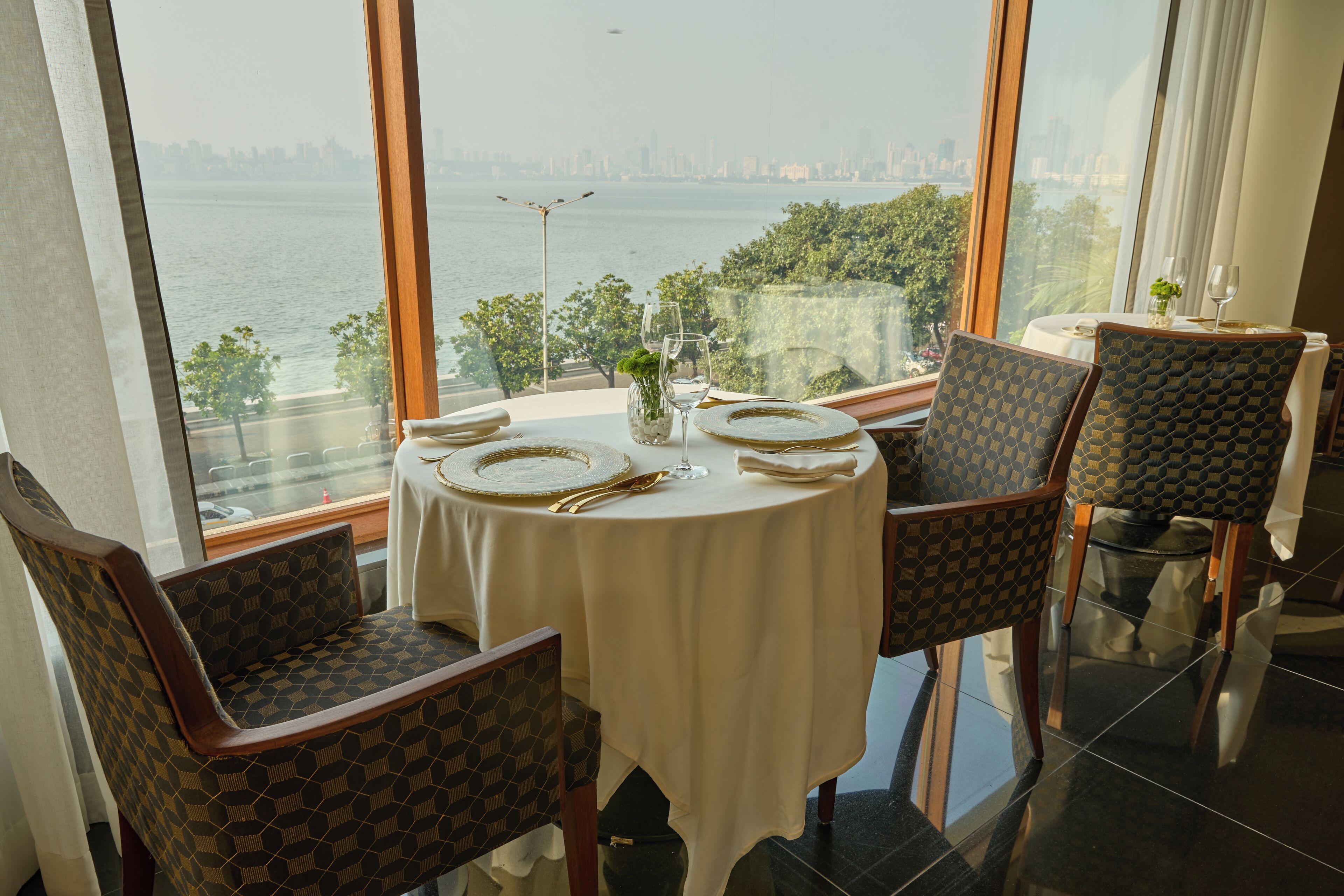 A dining area with a table set for two, chairs, and a view of a body of water.