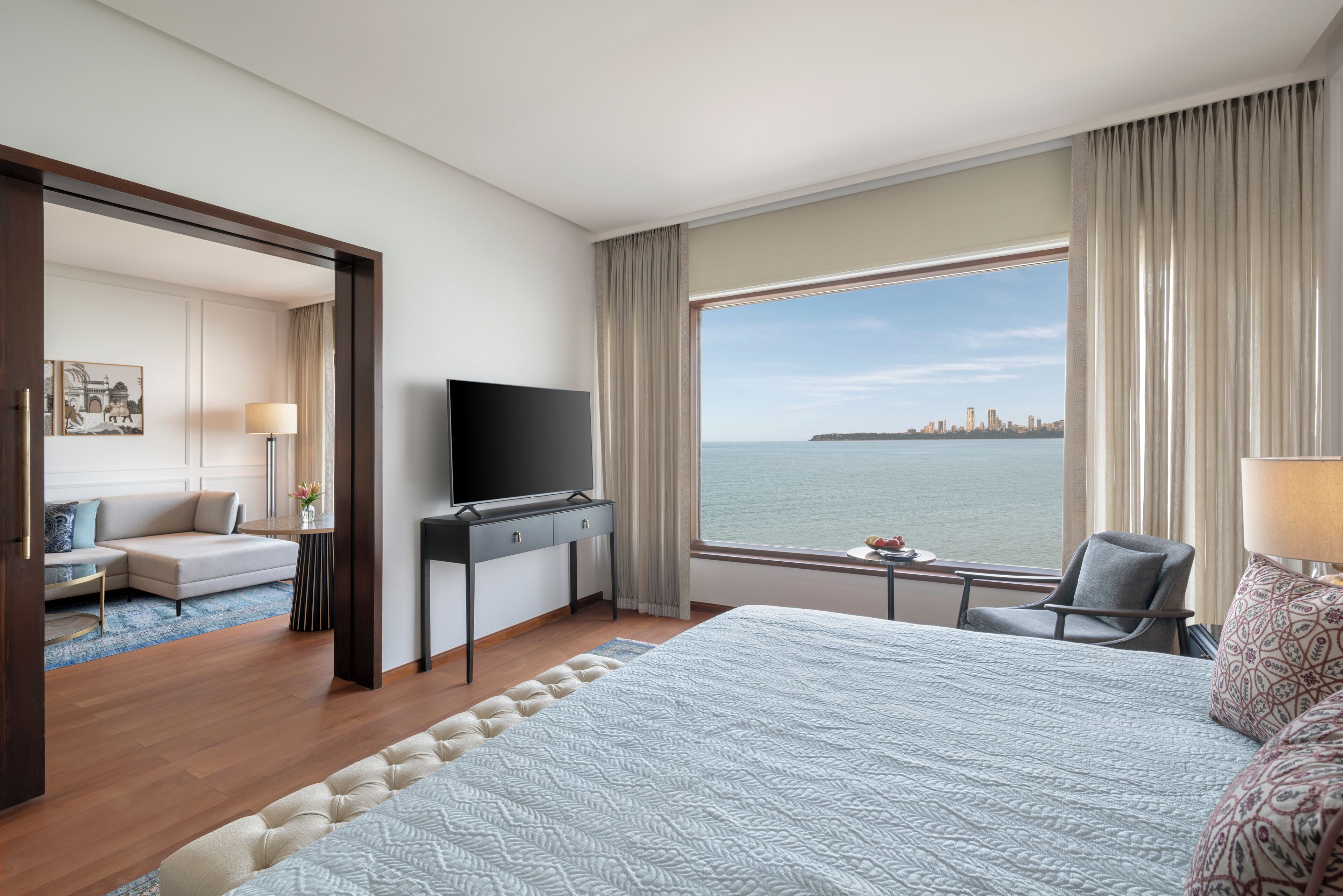 Habitación de hotel con una cama grande, un escritorio, un televisor, una silla y vistas a la silueta urbana.