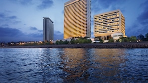 A modern hotel with a rectangular shape, multiple floors, and a flat roof. It is located near a body of water, reflecting the building's lights. - The Oberoi Mumbai (Mumbai)