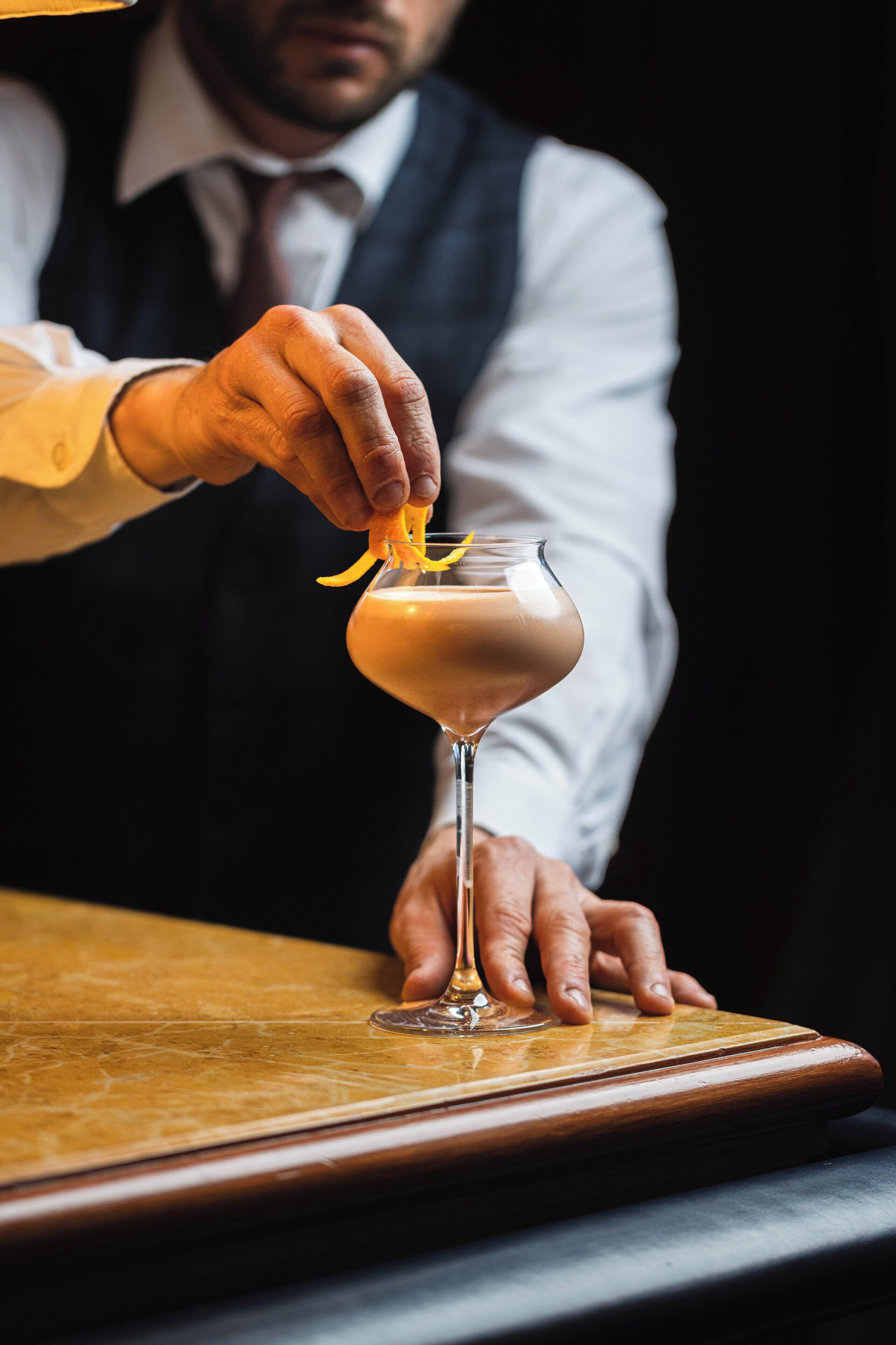 Una persona colocando una rodaja de limón en un cóctel en una copa de martini.