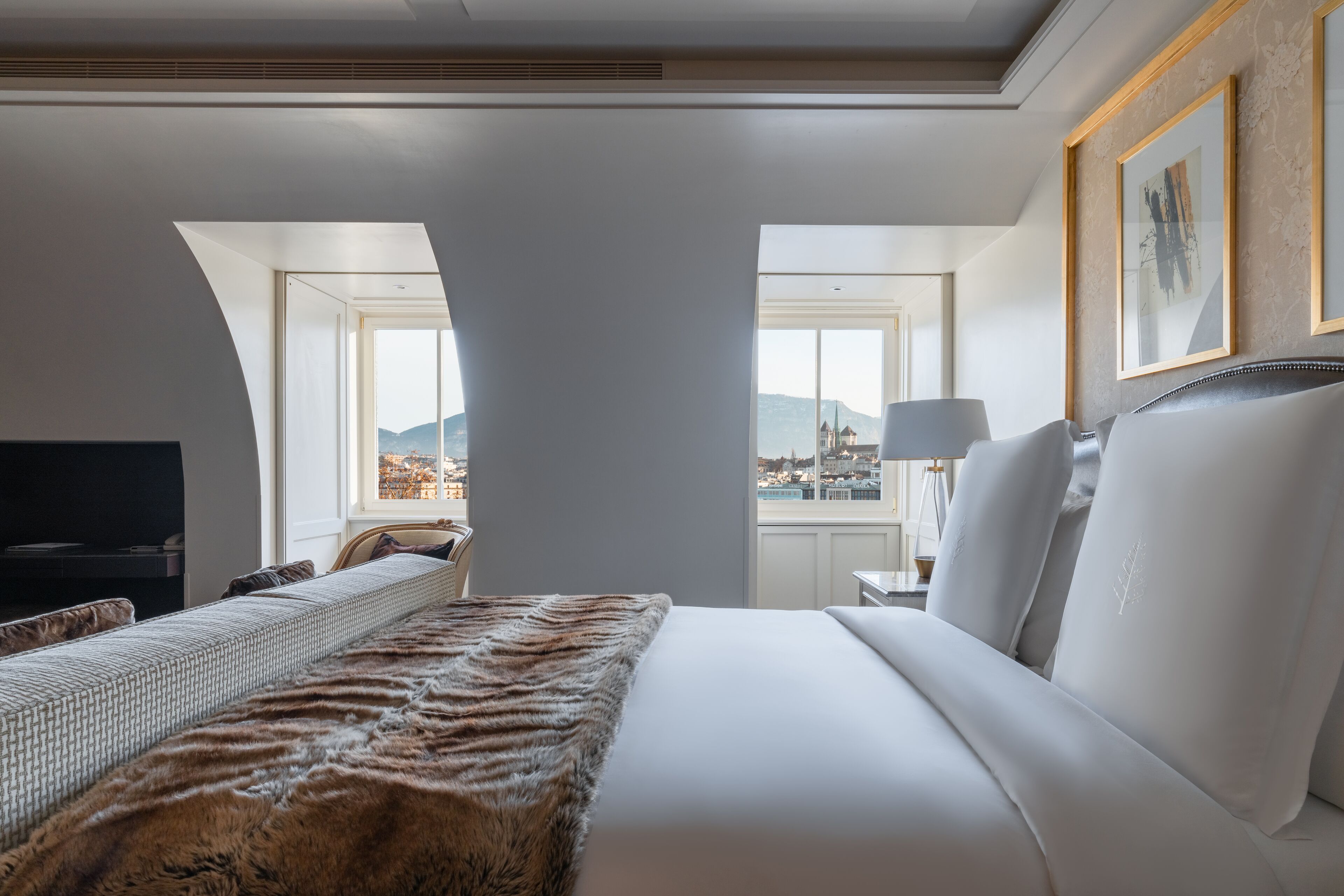 A hotel room with a large bed, a television, and a view of the city.