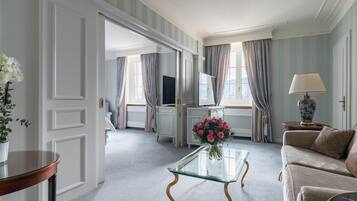 Un salón amplio con una mesa de centro de vidrio, un sofá color beige y un televisor al fondo.