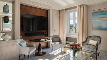 Un salon bien éclairé, doté d’un grand téléviseur à écran plat, de deux fauteuils, d’une table basse et d’une bibliothèque.
