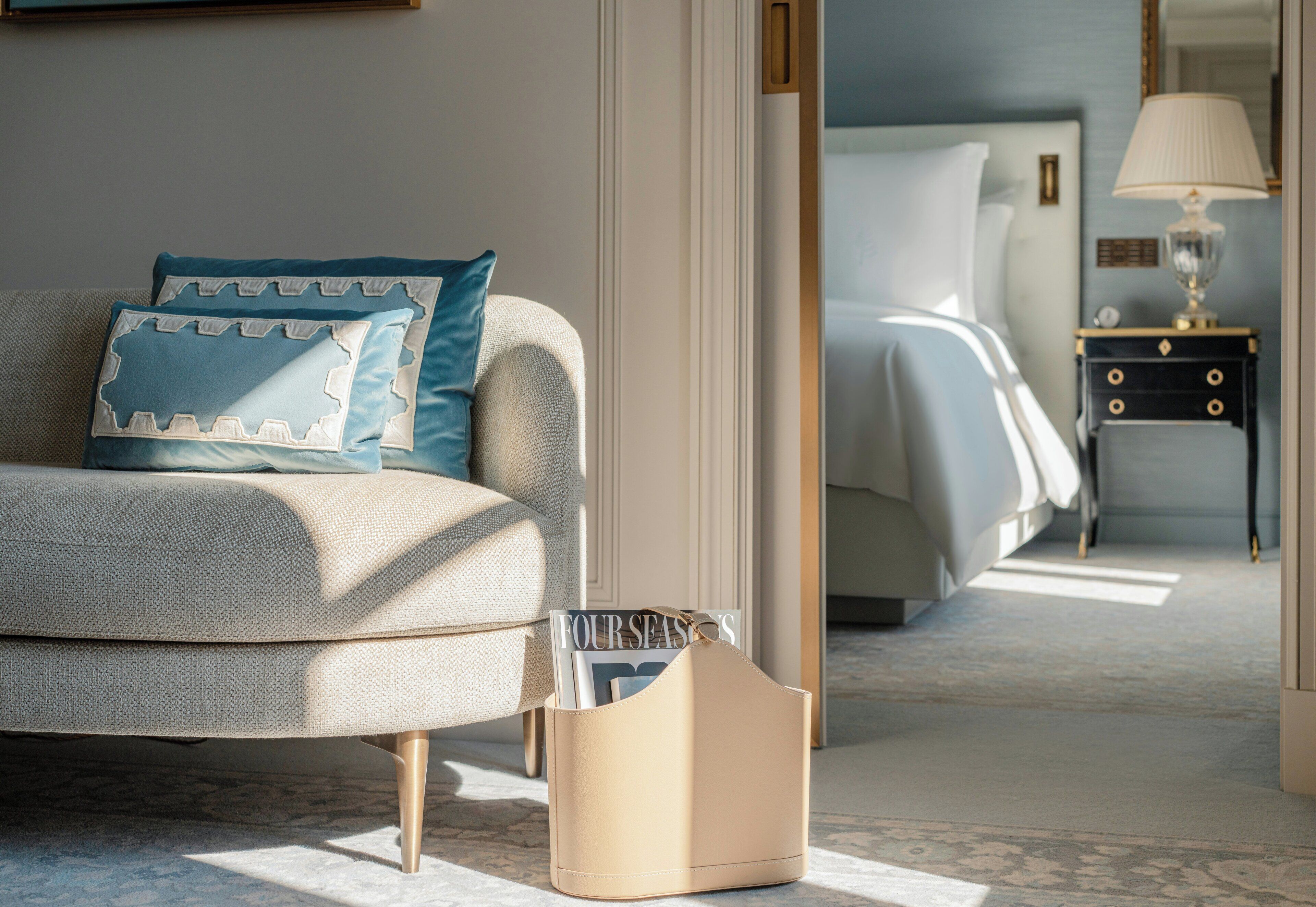 Quarto bem arrumado com uma cama, mesa de cabeceira com abajur e porta-revistas.
