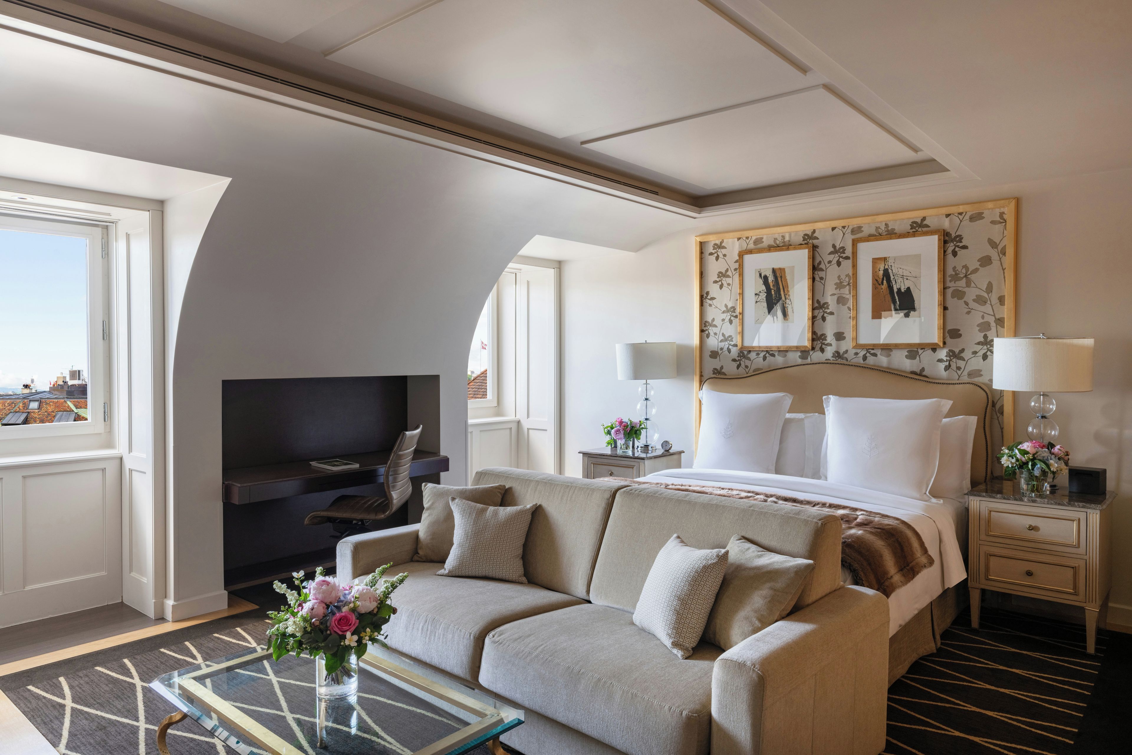 A hotel room with a bed, a sofa, a TV, and a nightstand with lamps.