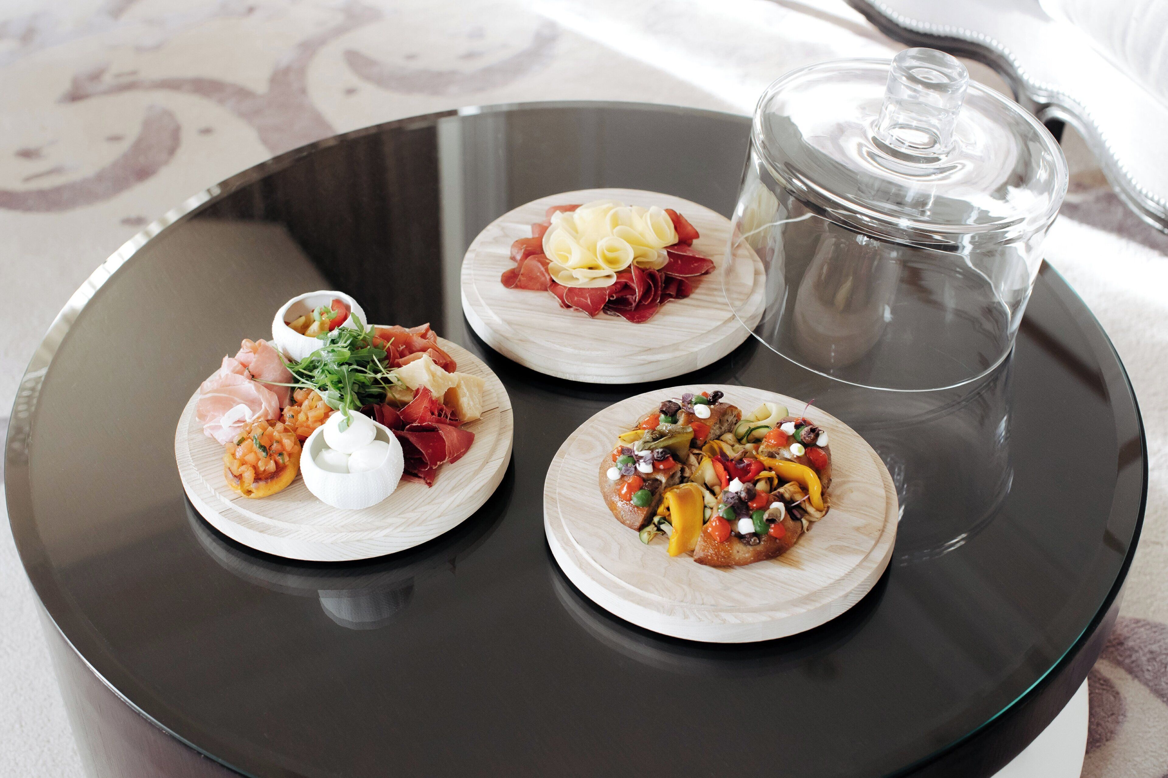 Tres pequeños platos de comida sobre una bandeja negra con un recipiente de vidrio transparente.