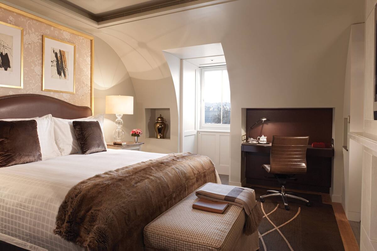 Une chambre d’hôtel avec un grand lit, un bureau, une chaise, une télévision et une cheminée.