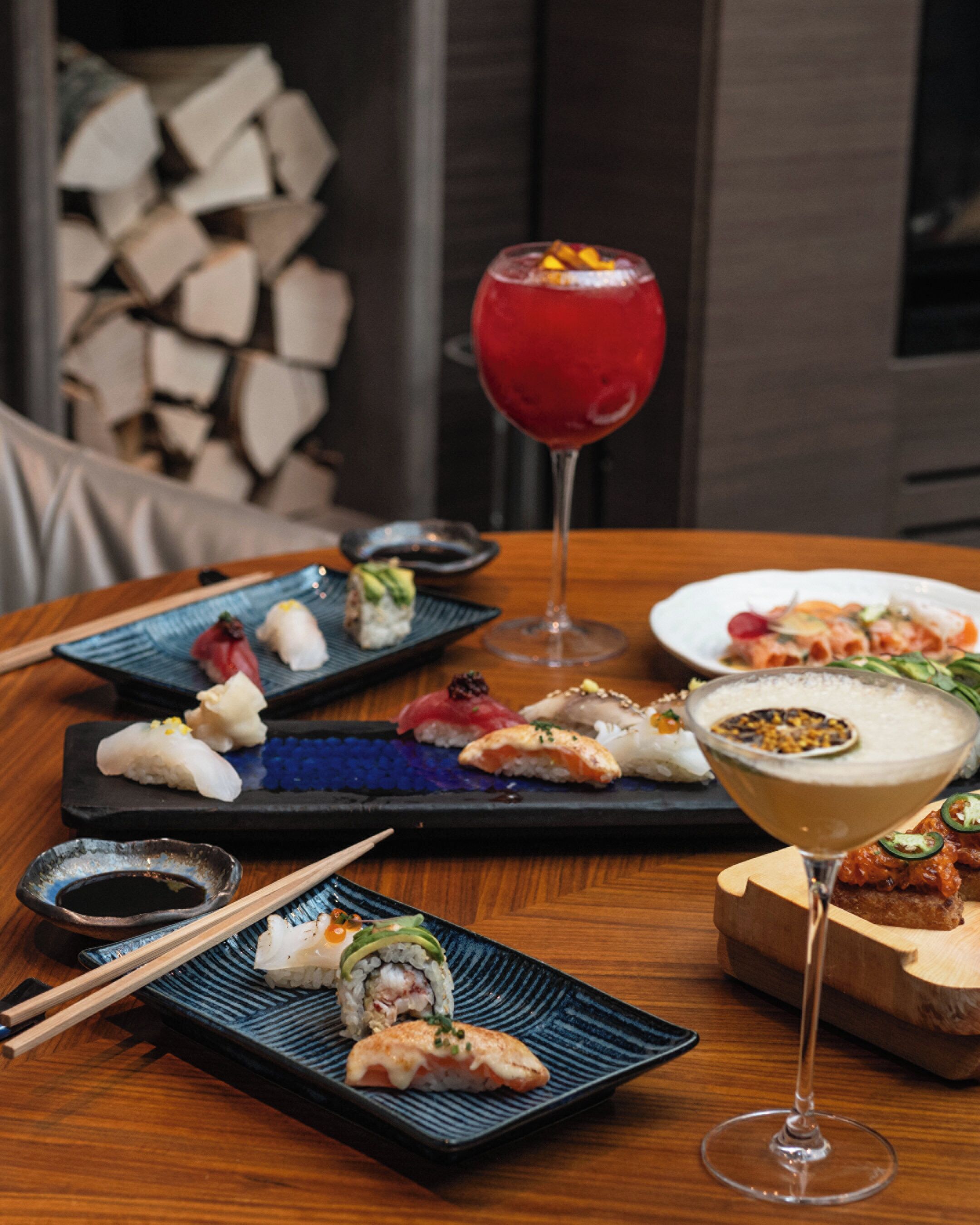 Una mesa con diversos platos, entre ellos sushi y una copa de martini.